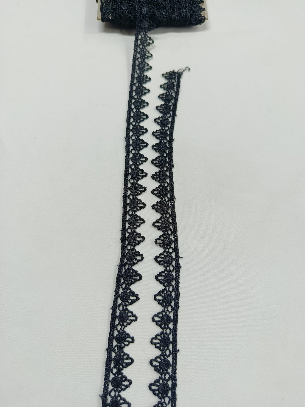 Detaliu dantelă neagră cu margini în colțuri mici, lățime 1,5 cm, ideală pentru croitorie și decorațiuni textile.