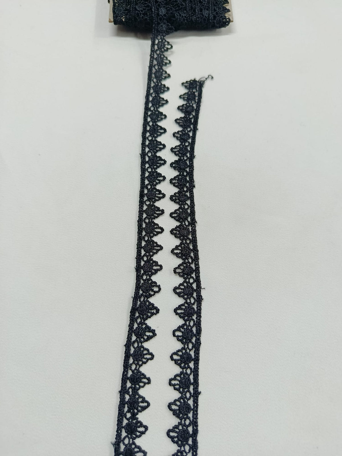 Detaliu dantelă neagră cu margini în colțuri mici, lățime 1,5 cm, ideală pentru croitorie și decorațiuni textile.