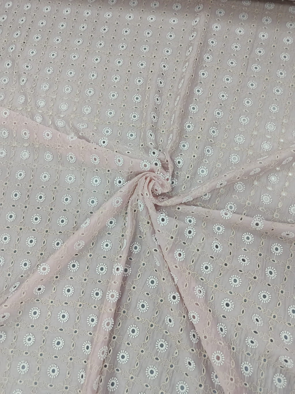 Prim-plan al broderiei sparte pe material Lyocell roz deschis
