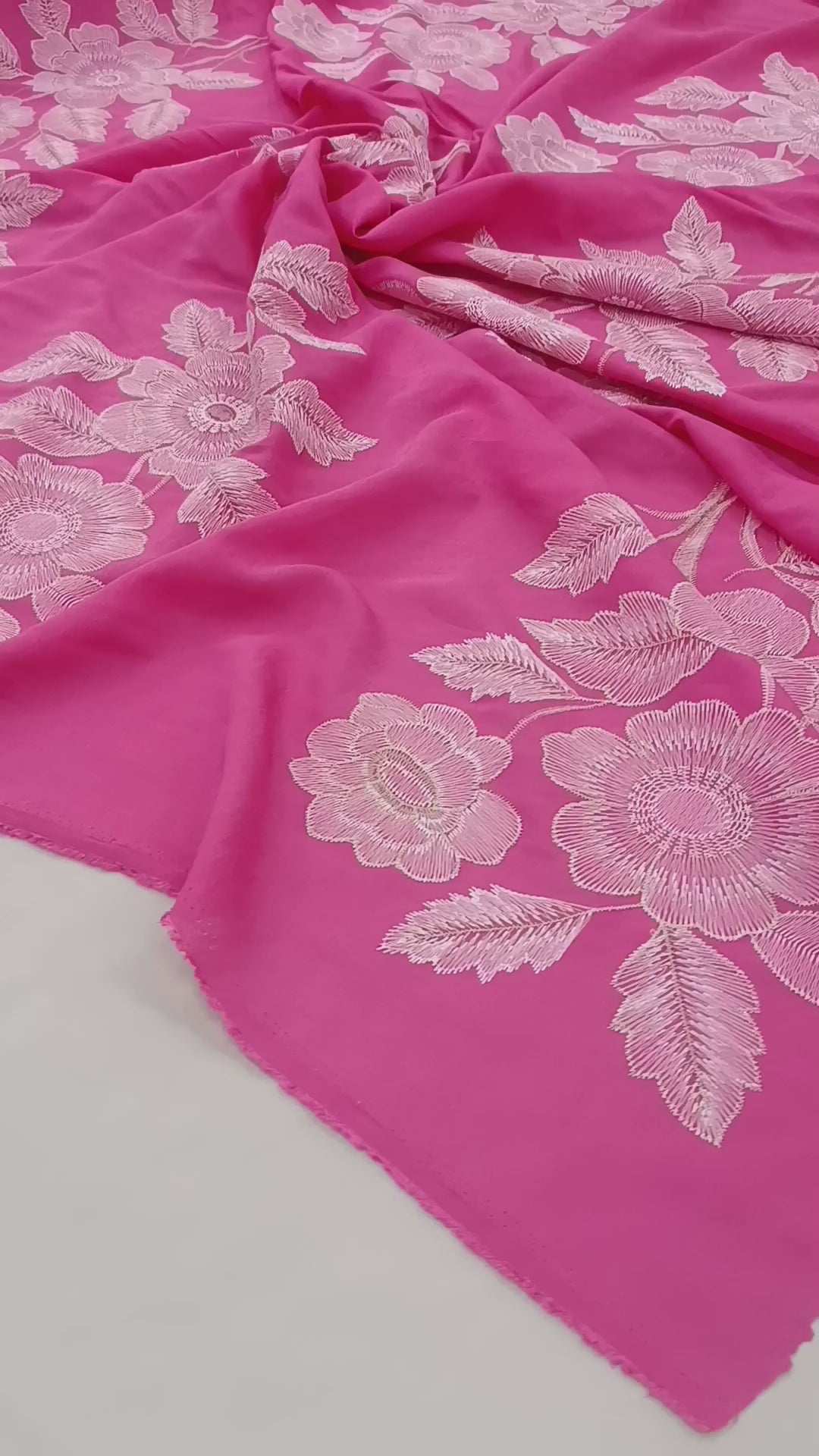 Detaliu al texturii materialului din bumbac liocel cu broderie roz.