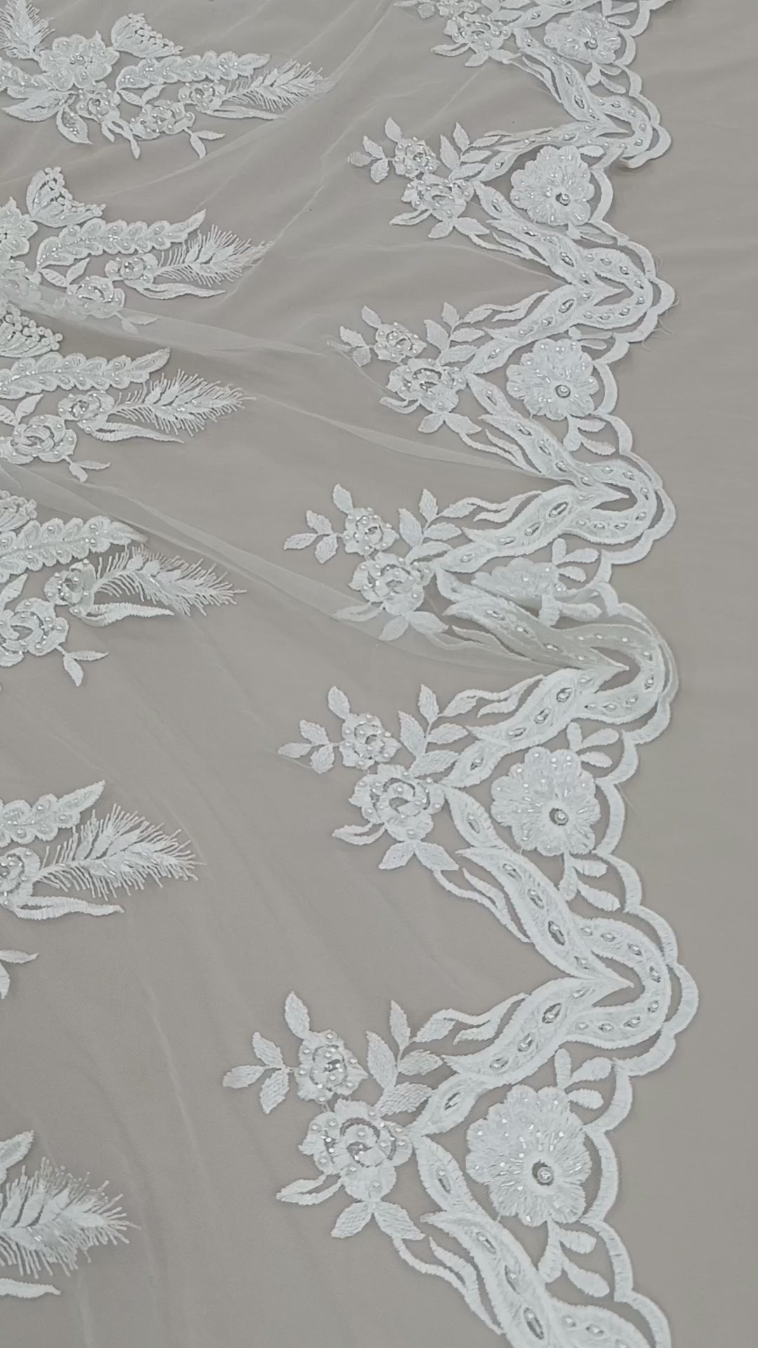 Prim-plan al broderiei premium cu perle și pietre pe tul alb.