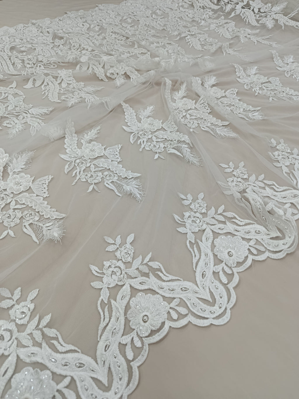 Textura delicată a tulului alb brodat cu perle și pietre.