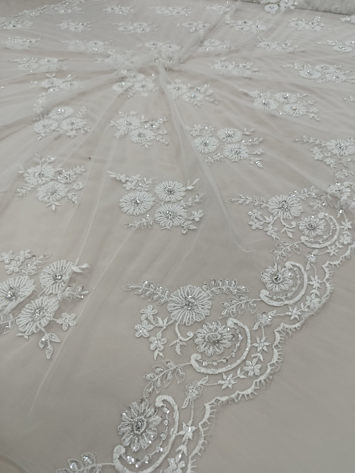 Detaliu al broderiei florale 3D cu pietre tubulare și cristale pe tull alb premium