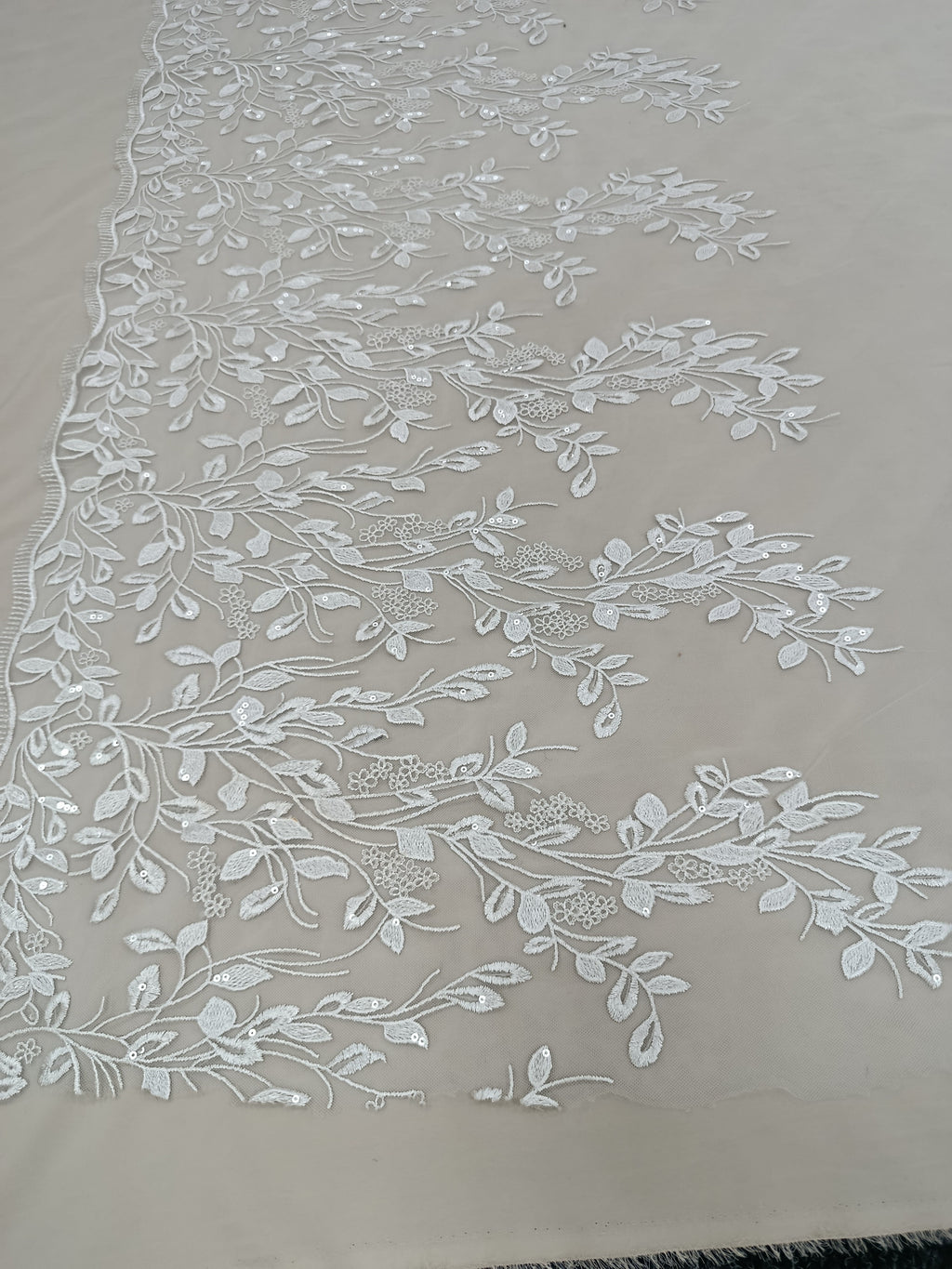 Textura delicată a tullului brodat cu paiete albe.