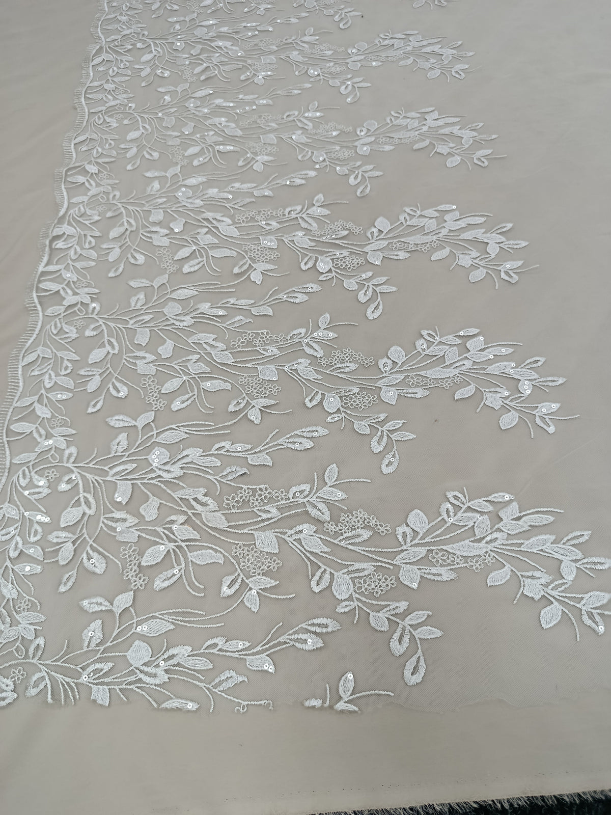 Textura delicată a tullului brodat cu paiete albe.